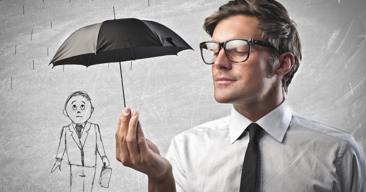 Man holding an amusingly small umbrella over a drawing of a man, illustrating insurance coverage